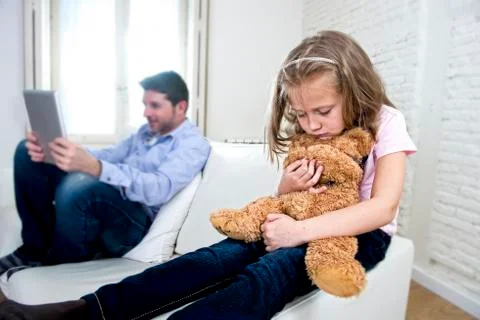 Young internet addict father using digital tablet  ignoring little sad daughter Stock Photos