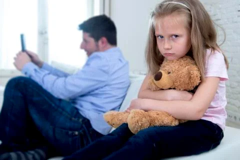 Young internet addict father using mobile phone ignoring little sad daughter Stock Photos