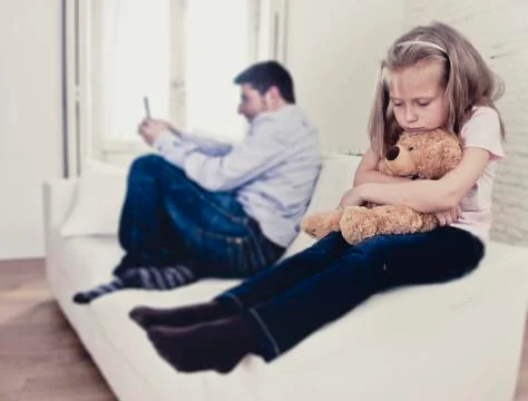 Young internet addict father using mobile phone ignoring little sad daughter Stock Photos
