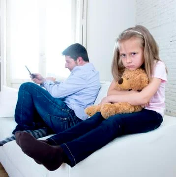 Young internet addict father using mobile phone ignoring little sad daughter Stock Photos