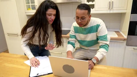 Young interracial couple managing finances together in a kitchen Stock Footage 334134119