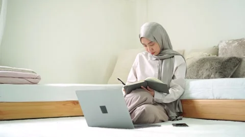 Young islam girl learn study write book notebook laptop remote work from home Stock Footage 299179652