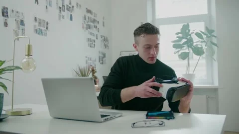 Young IT developer talks against laptop holding VR glasses Video stock 156193663