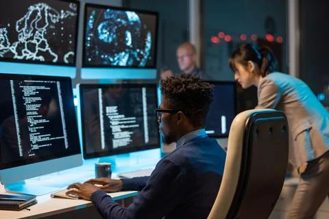 Young it-engineer decoding data while sitting in front of computers Stock Photos