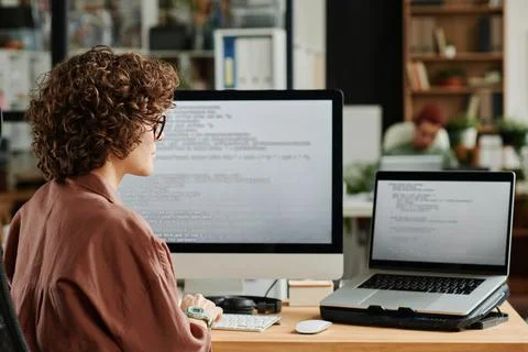 Young IT engineer looking at laptop screen with coded data Stock Photos