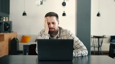A young IT guy is very tired or upset, he works at a computer Stock Footage 173474166