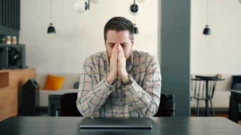A young IT guy is very tired or upset, he works at a computer Stock Footage 173474314