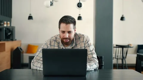 A young IT guy works at a computer and rejoices, he won Stock Footage 173474919