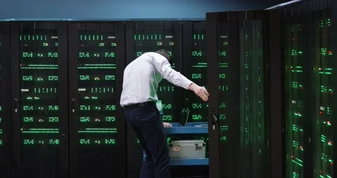 Young IT programmer with glasses opens cabinet with computer servers, checks Stock Footage 148397162