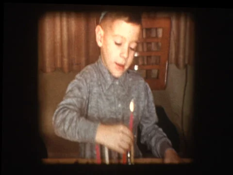 Young jewish boy lights Hanukkah candles in Menorah Stock Footage