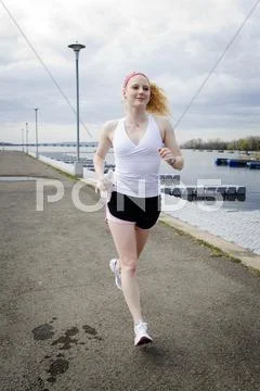 Young jogger running along water Stock Photos