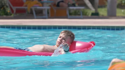 Young joyful child boy having fun swimming on inflatable air mattress in Vidéo 170181536