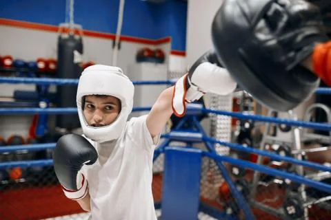 Young kickboxer developing accuracy while hitting the coach Stock Photos