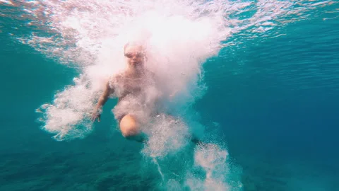 Young kid, boy jumps into the pool and dives with swimming goggles. 7 year old Stock Footage 268627887