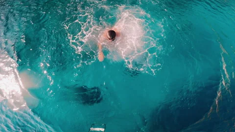 Young kid, boy jumps into the pool and dives with swimming goggles. 7 year old Stock Footage 268631391