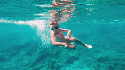 Young kid dives and dances in the sea. 7 year old kid swimming and having fun in Stock Footage 268630525