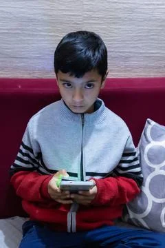 Young kid facial expression while watching mobile and playing online game a.. Stock Photos