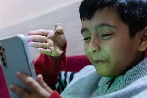 Young kid facial expression while watching mobile and playing online game a.. Stock Photos