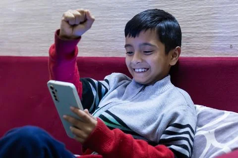 Young kid facial expression while watching mobile and playing online game a.. Foto stock