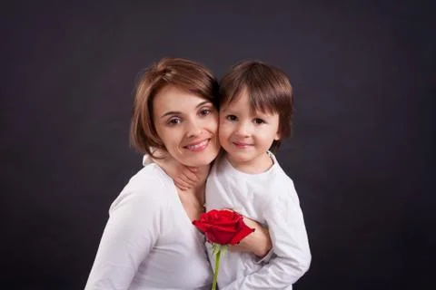 Young kid giving gorgeous red rose to his mom Stock Photos