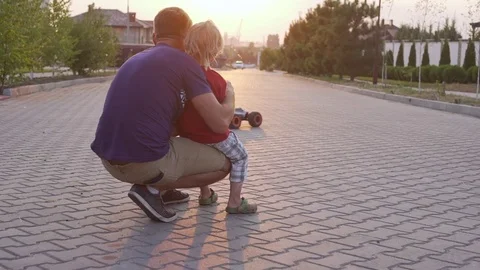 Young kid playing and his father playing with radio controlled car outside while Stock Footage 71787631