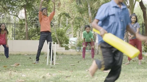 Young kid running by hitting the ball while playing cricket at park for scoring Vídeo Stock 192890968