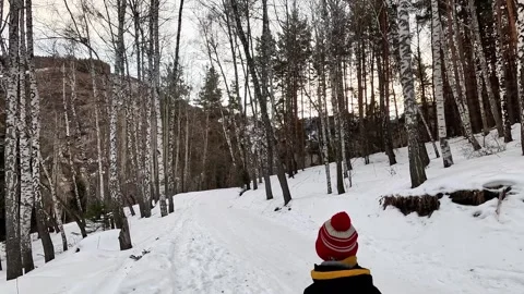 Young kid walking along snowy mountain trail in winter Stock Footage 331573764