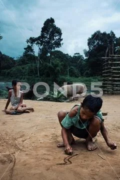 Young kids drawing buddhist symbols and art in the sand while a large passes Stock Photos
