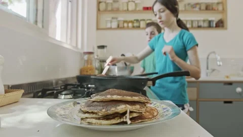 Young kids preparing pancakes in the kitchen using a frying pan Stock Footage 133930375