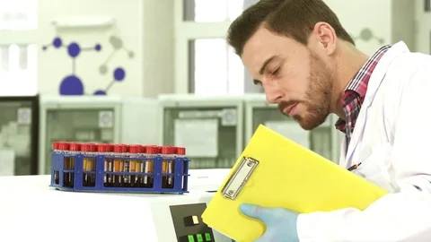A young laboratory assistant takes out test tubes with analyzes and rewrites Stock Footage 84865130