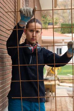 Young labourer looking at the camera in construction patio with iron mesh Stockfoto's