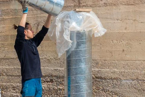 Young labourer man joining two air conditioning ducts on a construction site Stockfoto's