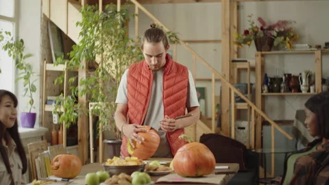 Young ladies are looking how a man is carving a pumpkin neatly Stock Footage 170403964