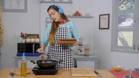 A young lady adding red chili powder and salt to the food in the pan while he... Stock Footage 156432944