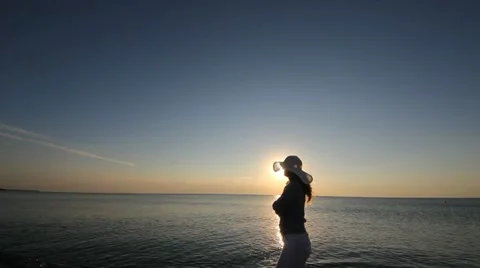 Young lady with a big hat walking on the beach at sunrise (sound) Stock Footage 12273343