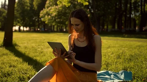 Young lady browsing her tablet in the park. Stock Footage 97882635