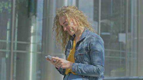 Young lady checking smartphone while standing next to office building Stock Footage 143026611