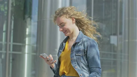 Young lady checking smartphone while standing next to office building Stock Footage 143029435