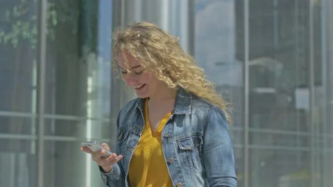 Young lady checking smartphone while standing next to office building Stock Footage 143031706
