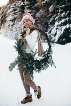 Young lady with christmas wreath in winter forest Stock Photos