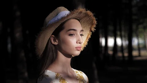 Young lady in cute straw hat against shady park slow motion Stock Footage 121061727
