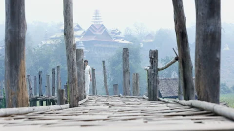 A young lady dressed in white is strolling along a wooden bridge on an early Stock Footage 247204522