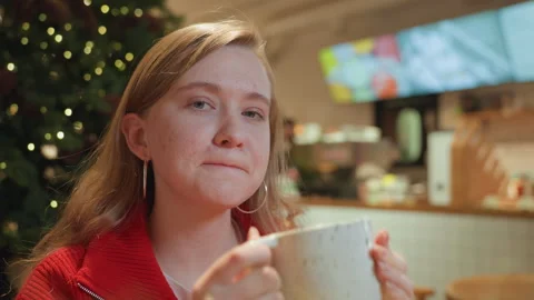 Young lady drinks coffee indoors. Female enjoying warm beverage inside cafe Stock Footage 345172803