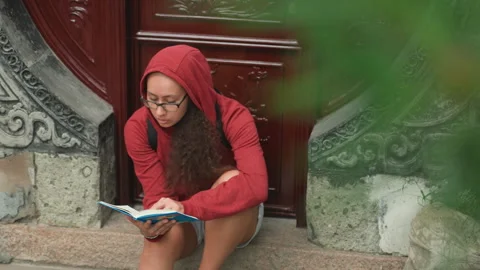Young lady examining map outside historic building. Young woman in vibrant Stock Footage 335161237