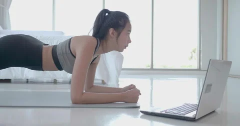 Young lady exercise workout plank use laptop to watching yoga and weight Video stock 150787074