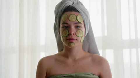 Young Lady Focused with Cucumber Slices on Face and Hair Wrapped in Towel Stock Footage 308593703