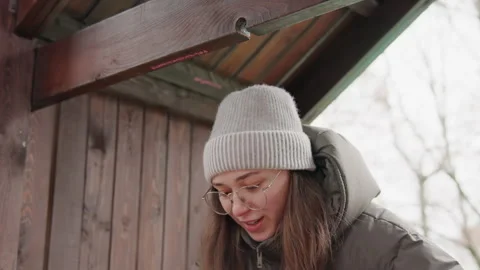 Young lady with glasses exploring cozy winter setting near door. Teenager with Stock Footage 345539704