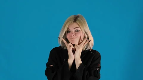 Young lady has fun by pressing cheeks and making lips into bow Stock Footage 306504717