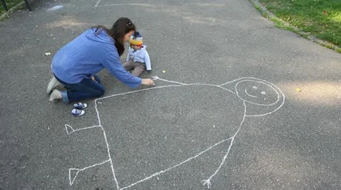 Young lady learning her son to draw with chalk on the asphalt Stock Footage 12303702
