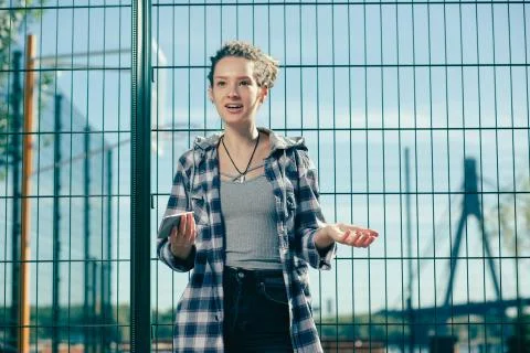 Young lady looking surprised while standing with her smartphone Stock Photos